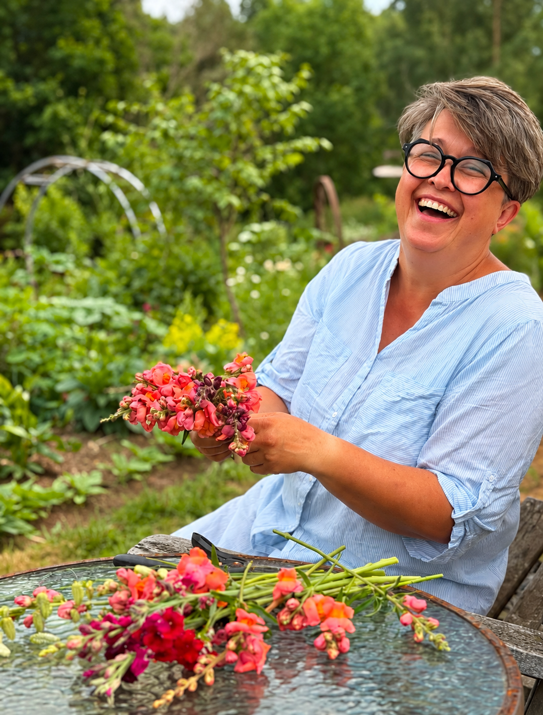 Maria håller en bukett i den blommande trädgården